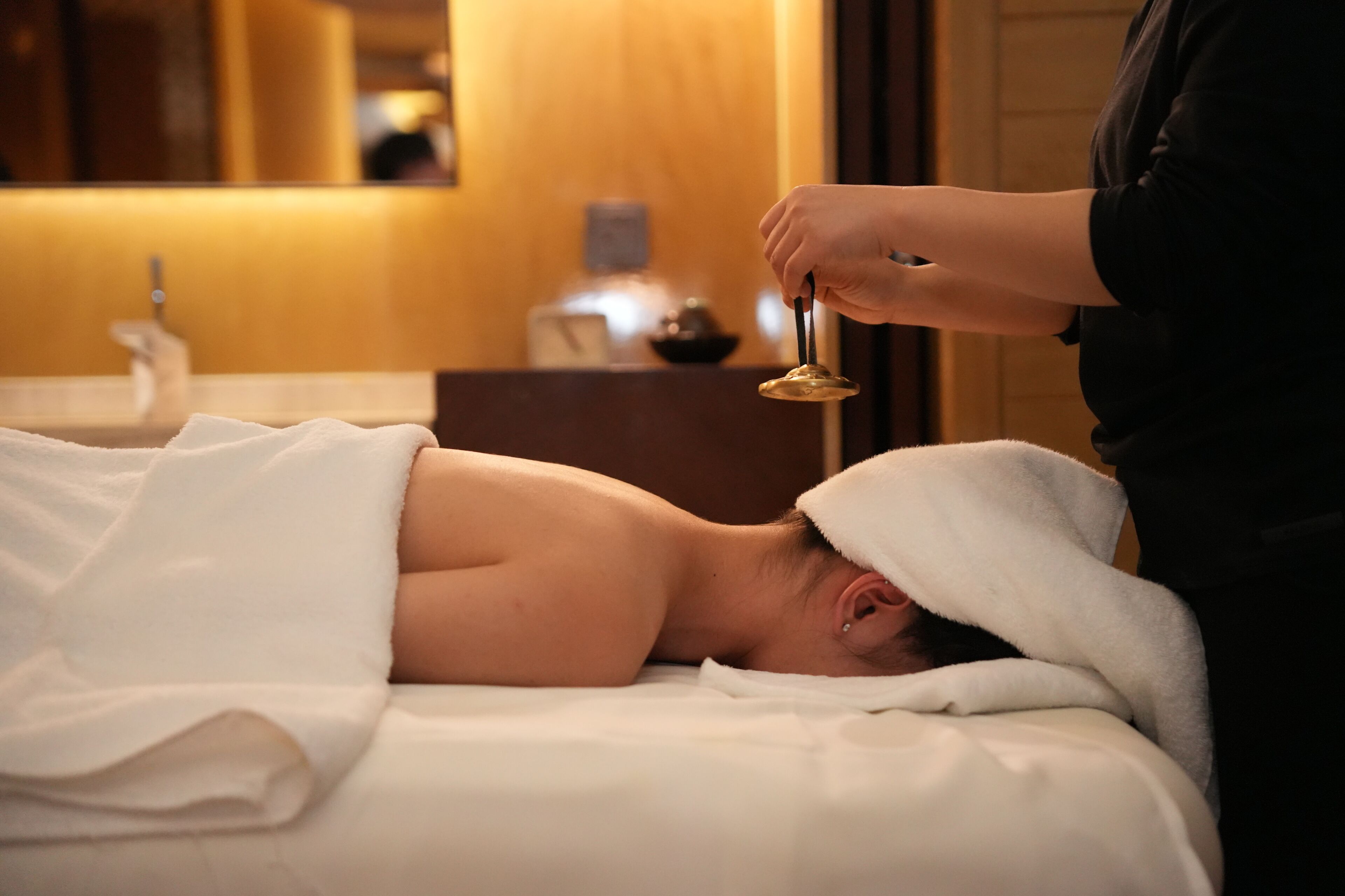 A person lying on a bed in a room with a wooden wall and a mirror.