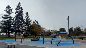 A playground with blue and red equipment, a bench, and a sign that reads 'PORT DARLINGTON.'
