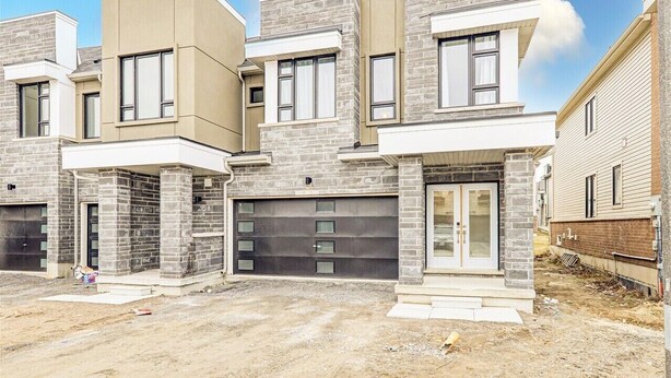 A modern multi-story residential building with a garage, large windows, and a flat roof.
