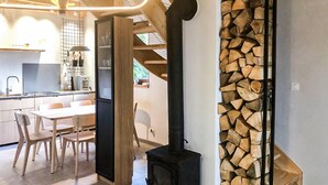 Eine moderne Küche mit Essbereich, einem schwarzen Kaminofen und einem Holzstapel.