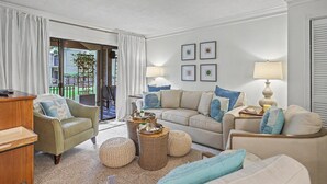 A living room with a sofa, armchairs, a coffee table, and a lamp. - Beyond Measure by Sandpiper | Near Beach (Seabrook Island)
