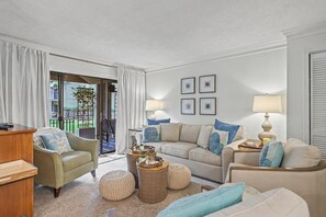 Ein Wohnzimmer mit einer Couch, Sesseln, einem Couchtisch und einer Lampe.