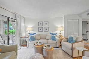 Ein Wohnzimmer mit einer Couch, zwei Beistelltischen, einem Couchtisch und einem Sessel.