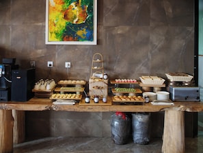 Un buffet proposant divers plats, une machine à café et un tableau accroché au mur.
