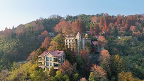 A multi-story building with a turret, surrounded by autumn foliage. - Mogan Dreamlohas Sunrise Resort Hotel (Huzhou)