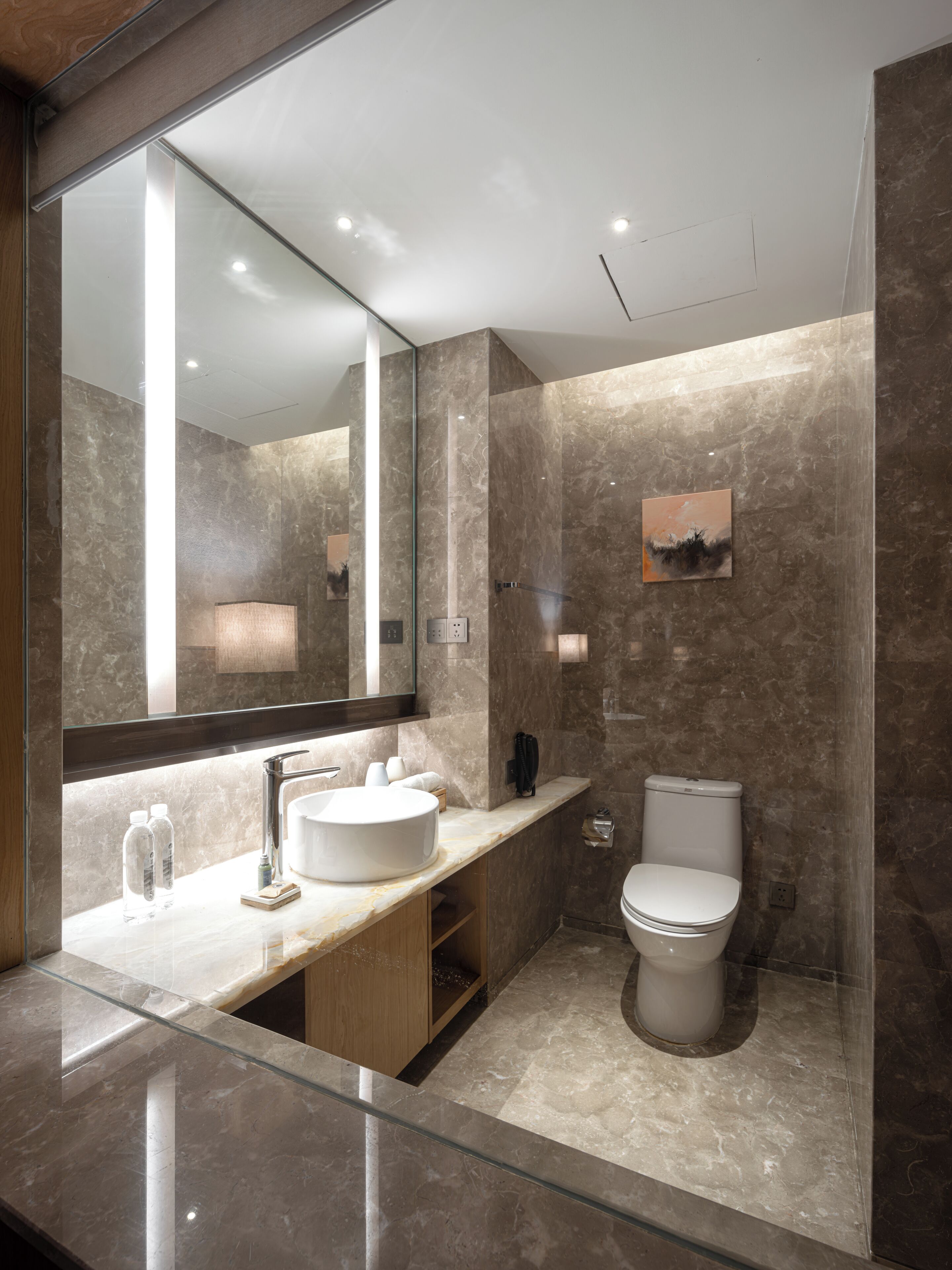 A modern bathroom with a large mirror, a round sink, a toilet, and a shower area.
