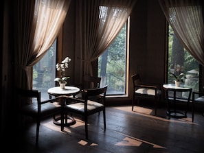 Une pièce avec un plancher en bois, deux tables rondes entourées de chaises, et une orchidée en pot sur chaque table.