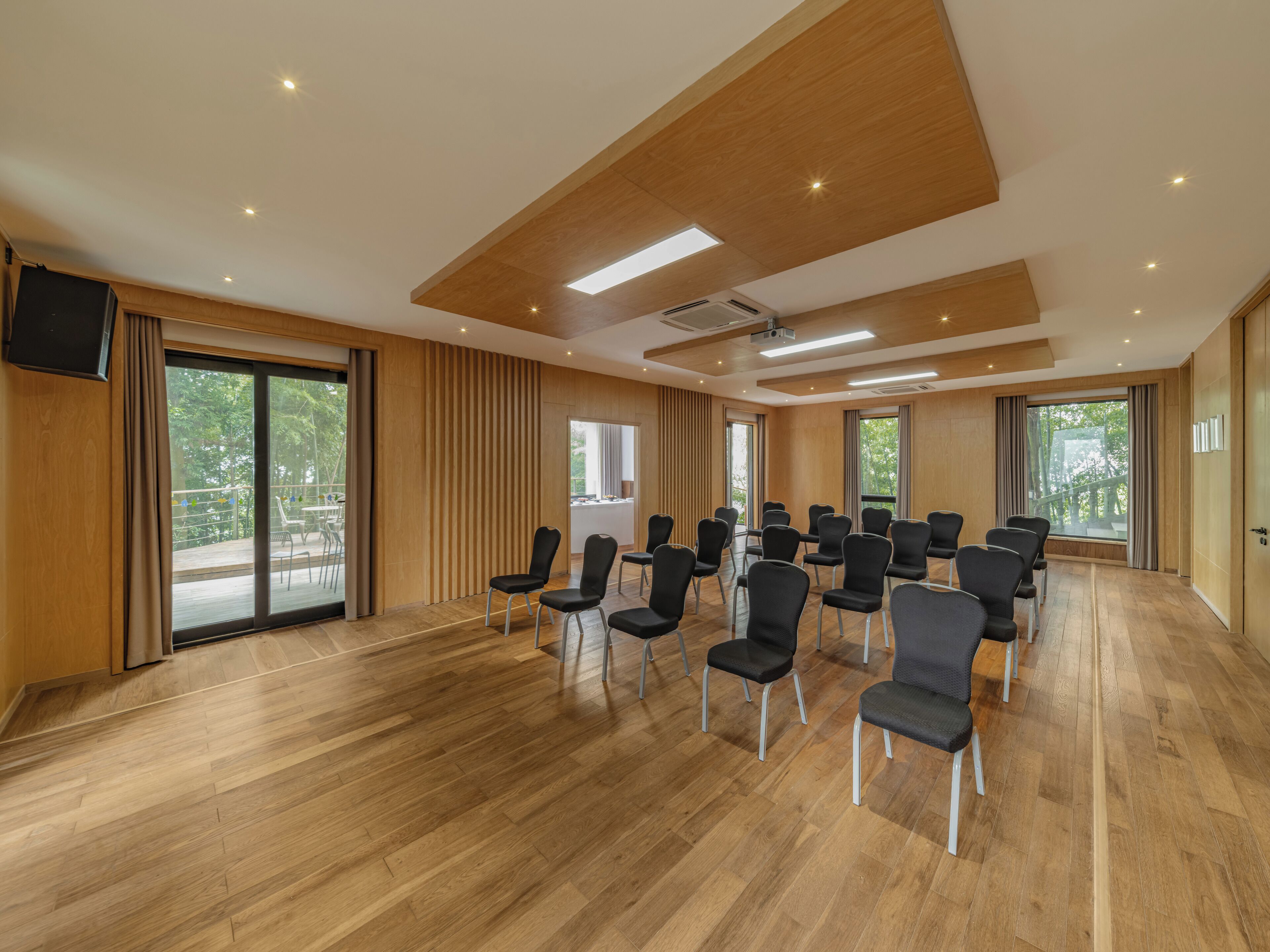 A conference room with wooden floors, black chairs, and large windows.