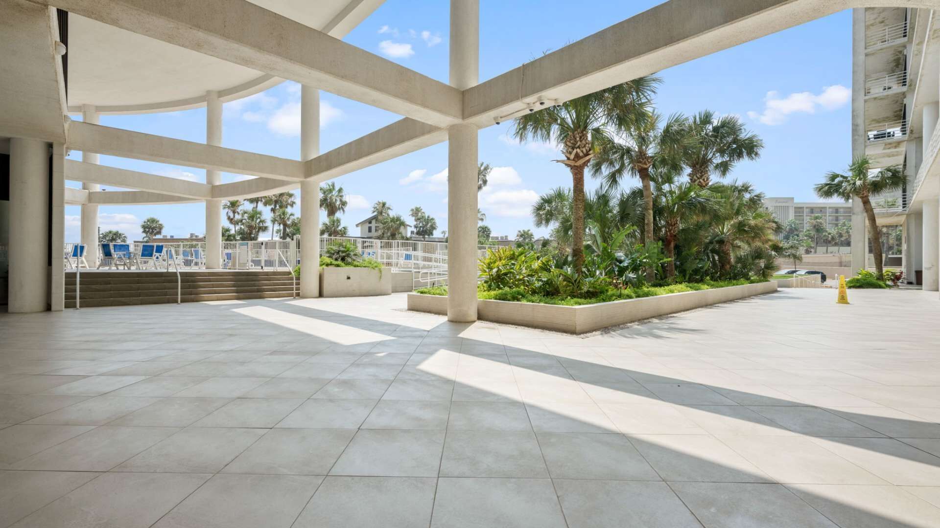 Un espace intérieur ouvert, doté d’un haut plafond, de piliers en béton et d’un sol carrelé.