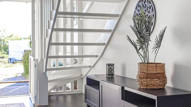 A modern interior with a staircase, a dark wooden cabinet, and a decorative plant. - Nice home in Smygehamn with WiFi (Smygehamn)