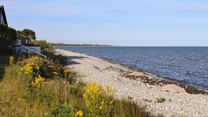 A pebbled beach with a house on the left, a clear sky, and calm sea. - Nice home in Smygehamn with WiFi (Smygehamn)