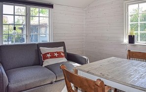 Una habitación con un sofá gris, una mesa de madera y una ventana que da a una vista de una casa.