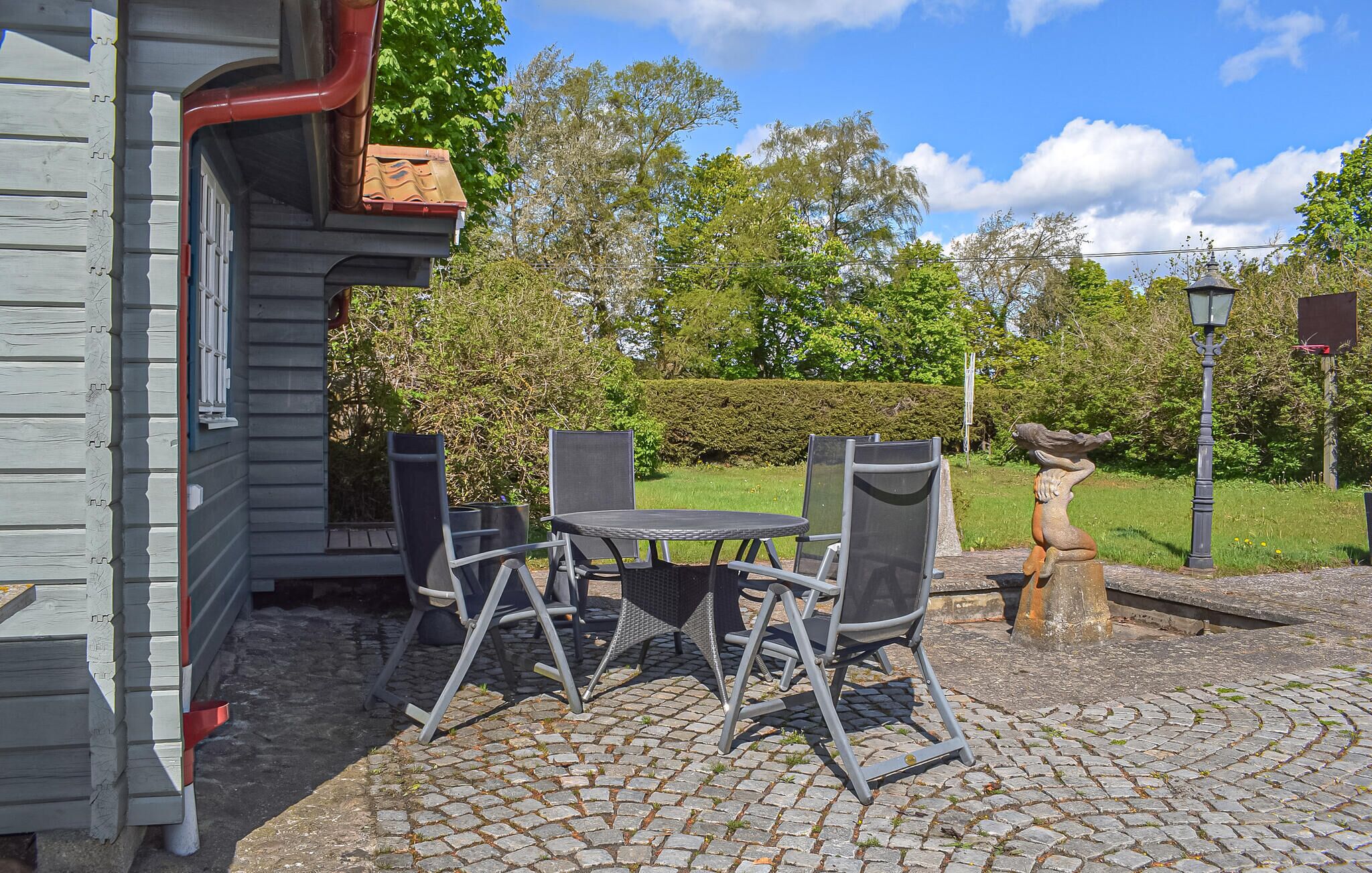 Une terrasse avec des meubles d’extérieur, une haie et un lampadaire.