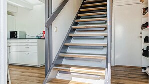 A staircase with wooden steps and metal railings, leading to a room with white cabinets and a kitchen area. - Amazing home in Tomelilla with WiFi (Tomelilla)