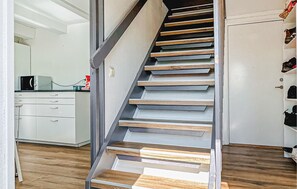 A staircase with wooden steps and metal railings, leading to a room with white cabinets and a kitchen area. - Amazing home in Tomelilla with WiFi (Tomelilla)