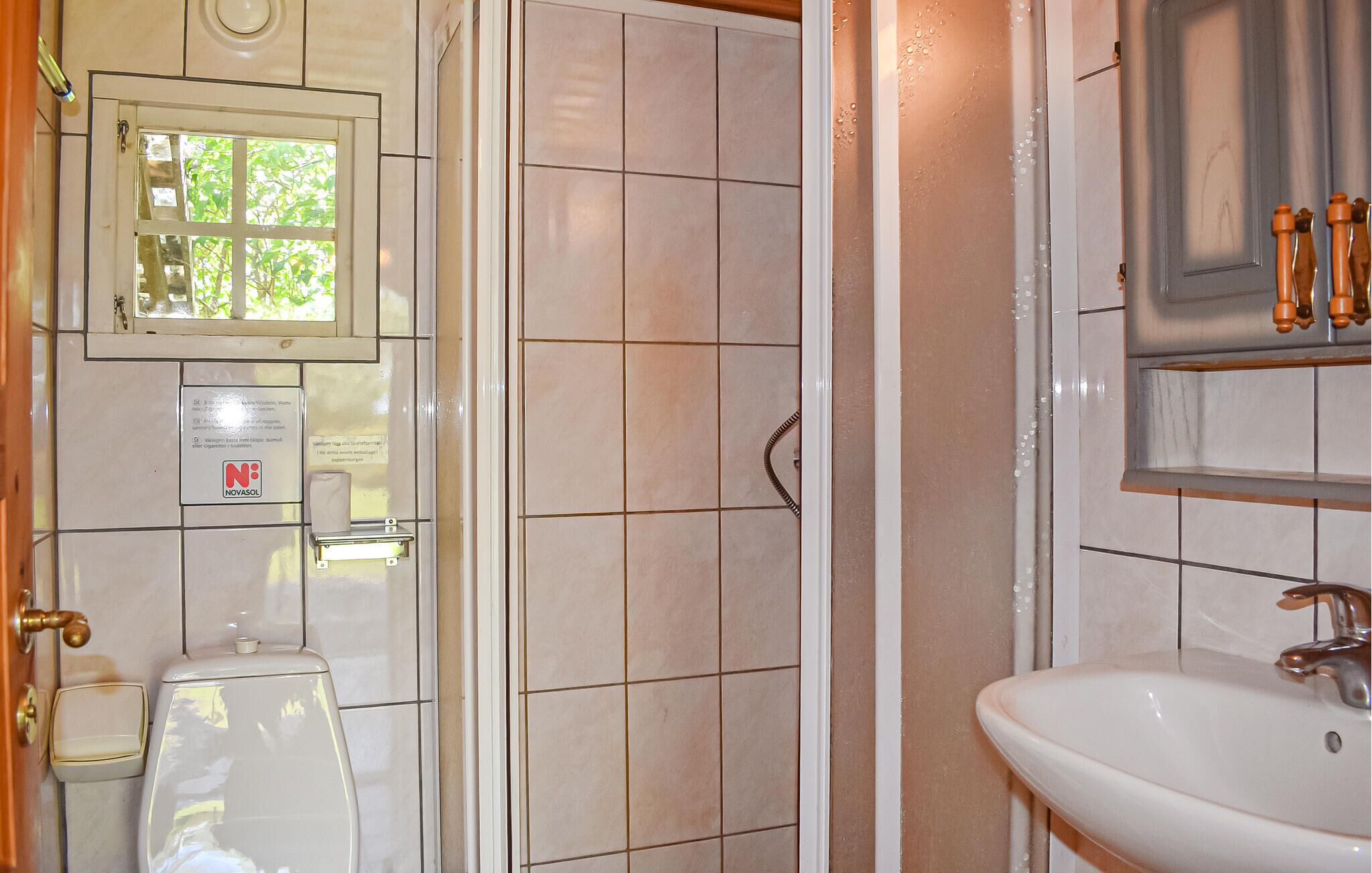 Et badeværelse med toilet, bruseområde og håndvask.