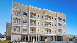Un edificio residencial de varios pisos con balcones, garaje y cielo despejado.