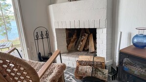 Una chimenea con leña, una rejilla de metal y un modelo decorativo de barco encima.