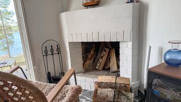 Un caminetto con tronchi di legna, una griglia metallica e un modellino di nave decorativo sopra.