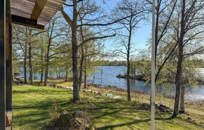 En utsikt över en sjö med träd, en gräsyta och en träkonstruktion.