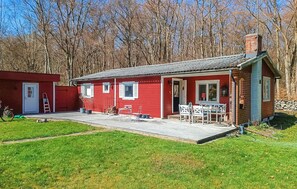Ein rotes Holzhaus mit Veranda, einer Tür und einem kleinen Garten.