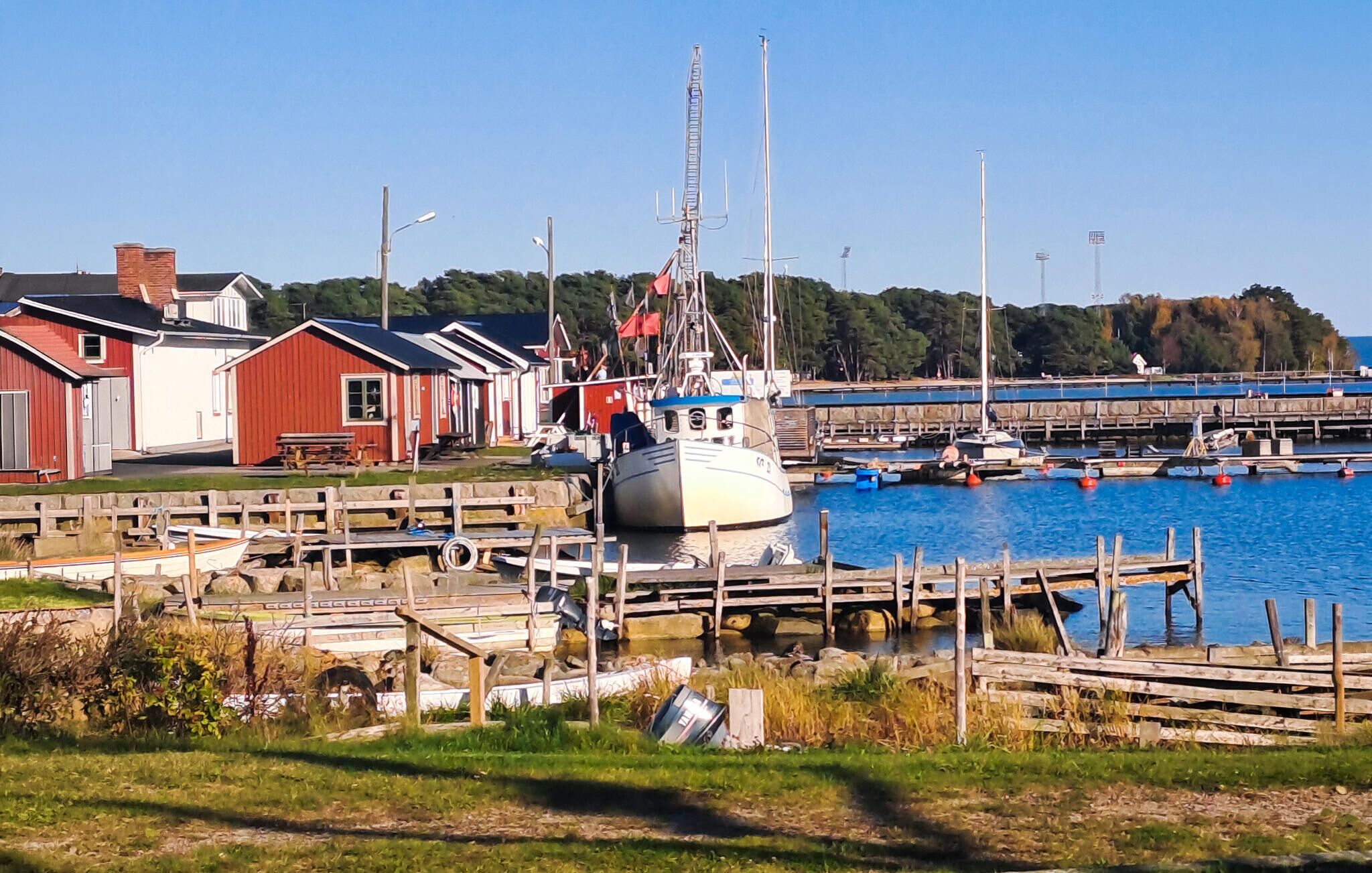 Un port de plaisance avec des bateaux amarrés, des passerelles en bois et des bâtiments rouges.