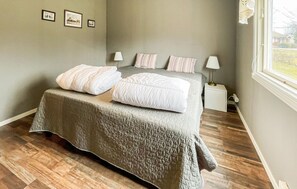 Een slaapkamer met een bed, nachtlampjes, een nachtkastje en een raam met uitzicht.