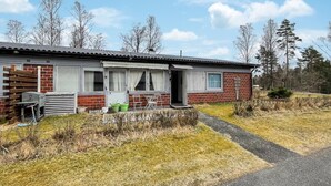 Et etplans murhus med en veranda, grill og en lille have.