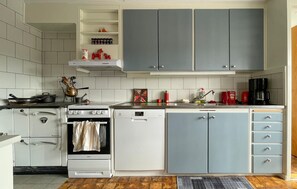 Eine Küche mit weißen und grauen Schränken, einem Herd, einem Backofen und einer Kaffeemaschine.