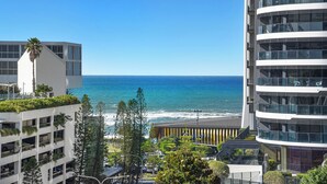 A modern building with a view of the ocean, featuring balconies with greenery, a parking area, and a clear sky. - Beach Holiday at Oracle Level 7 (Gold Coast)