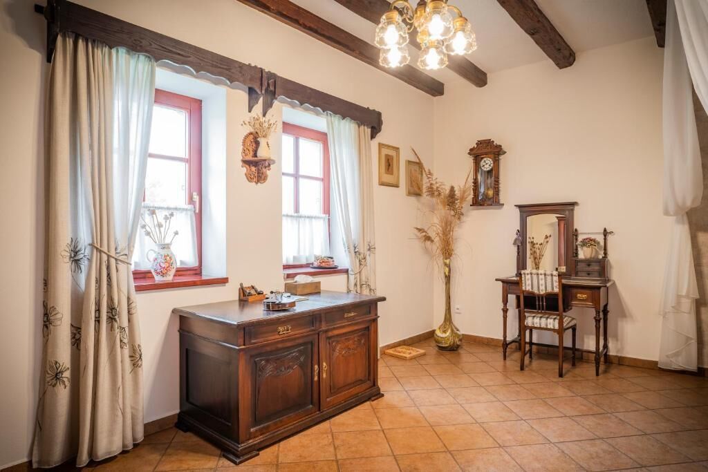Une pièce comprenant un meuble en bois, une chaise, un miroir et un grand vase contenant des plantes séchées.
