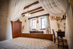 A bedroom with a bed, wooden headboard, a wooden dresser, a desk, and a chair. - Penzion Primášé (Dolní Věstonice)