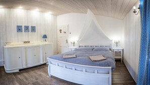 A bedroom with a white canopy bed, bedside tables, a dresser, and framed pictures on the wall. - Penzion Primášé (Dolní Věstonice)