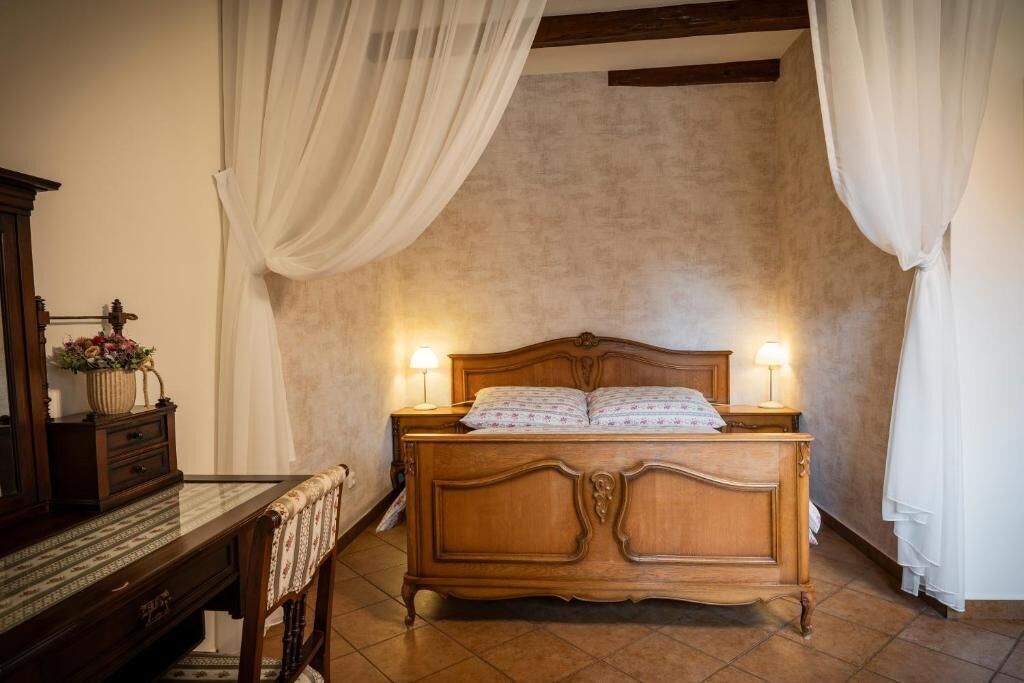 Ein Schlafzimmer mit einem hölzernen Bett, zwei Nachttischlampen, einem Nachttisch, einer Kommode und einem Tisch mit Blumen.