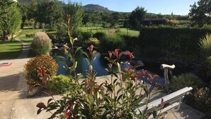 A garden with a pool, a wooden bench, and a view of a hill. - Penzion Primášé (Dolní Věstonice)