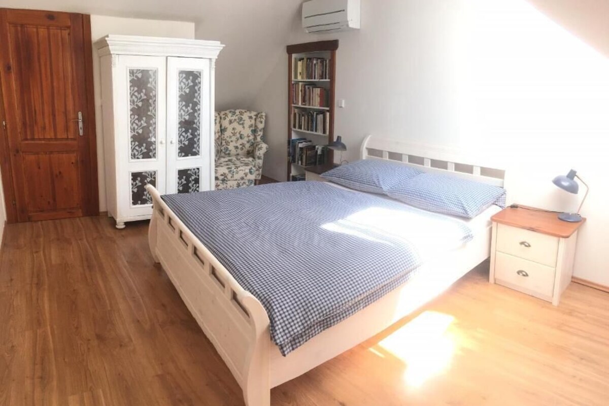 A bedroom with a bed, a wardrobe, a chair, a bookshelf, and a nightstand.