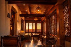 A traditional wooden interior with a sofa, tables, and a hanging light fixture. - The Riverside Barn Srinagar (Srinagar)