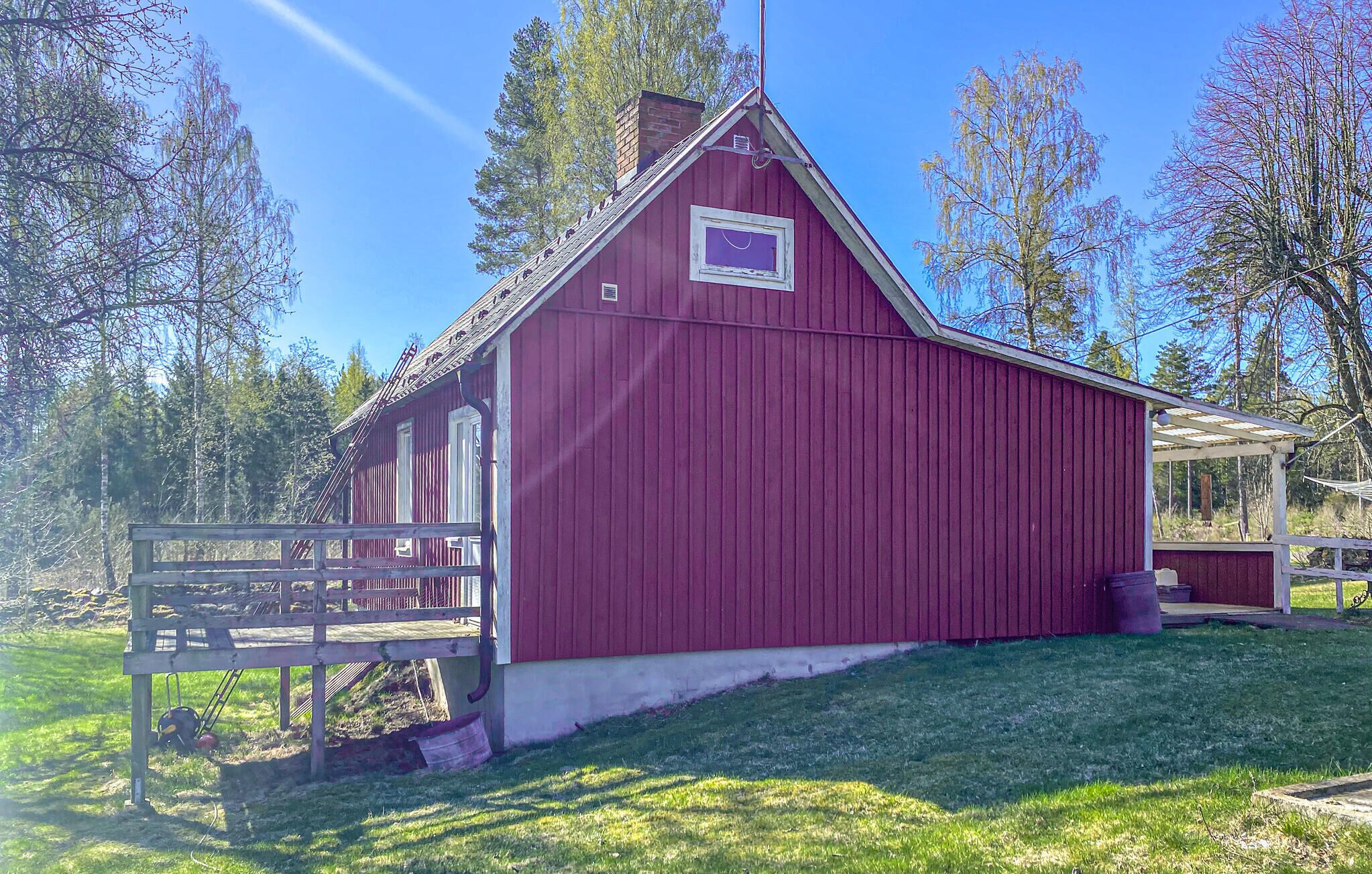 A red barn with a white door and windows, surrounded by grass and trees.