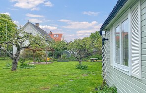 Ein Wohngrundstück mit Pergola, kleinem Garten und einem Haus mit rotem Dach.