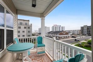 A balcony with a table and chairs, overlooking a street with buildings and a hotel named 'Saratoga Inn'. - Residence 201S at The Sandcastle Condominiums (Wildwood Crest)