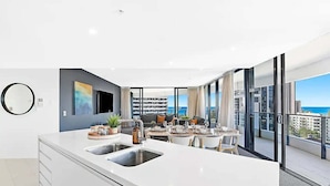Una cocina moderna con una isla grande, una zona de comedor y un balcón con vistas a la ciudad.