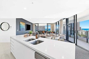 Eine moderne Küche mit einer großen Kochinsel, einem Essbereich und einem Balkon mit Blick auf die Stadt.