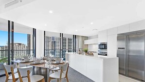 Una cocina moderna con comedor, ventanas amplias y vista a rascacielos.