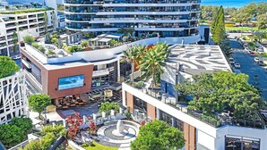 Un hotel moderno urbano con varios pisos, terrazas al aire libre y un patio central con una fuente.