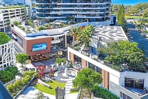Ein modernes Stadt-Hotel mit mehreren Etagen, Terrassen im Freien und einem zentralen Innenhof mit einem Brunnen.