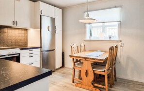 A modern kitchen with a built-in oven, a stainless steel refrigerator, and a dining table with wooden chairs. - Lovely apartment in Skärhamn with WiFi (Skärhamn)