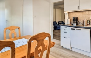 A compact kitchen with a wooden dining table and chairs, a white refrigerator, and a coffee maker. - Lovely apartment in Skärhamn with WiFi (Skärhamn)