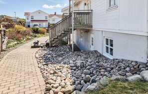 A residential area with a paved walkway, a wooden staircase, and a garden with rocks and plants. - Lovely apartment in Skärhamn with WiFi (Skärhamn)