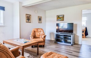 A living room with a leather armchair, a wooden coffee table, a flat-screen TV on a stand, and a painting on the wall. - Lovely apartment in Skärhamn with WiFi (Skärhamn)