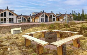 Eine Reihe von Holzhütten mit einem Kiesweg und Picknicktischen im Vordergrund.